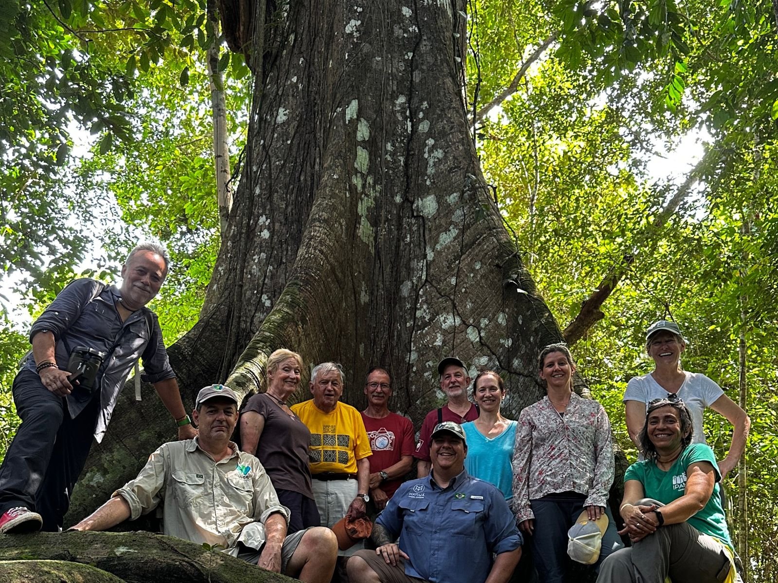 Ygor com um grupo de viajantes diante de uma sumaúma na Amazônia